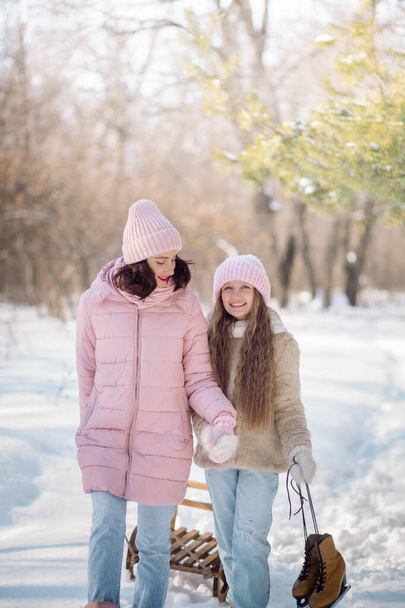 Cute curly girl of 10 years old and her young mother play in the snowy forest in winter - Foto, Imagen
