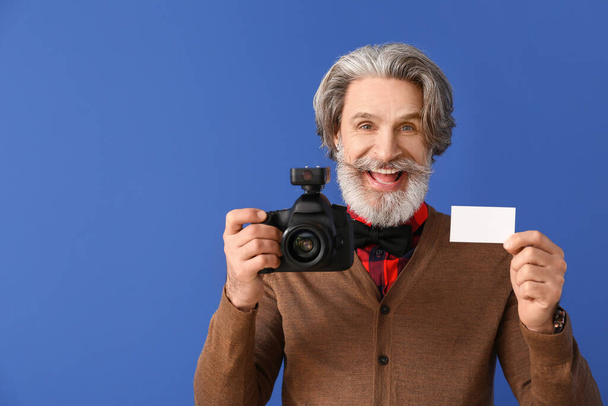 Handsome senior photographer with business card on color background - Foto, immagini