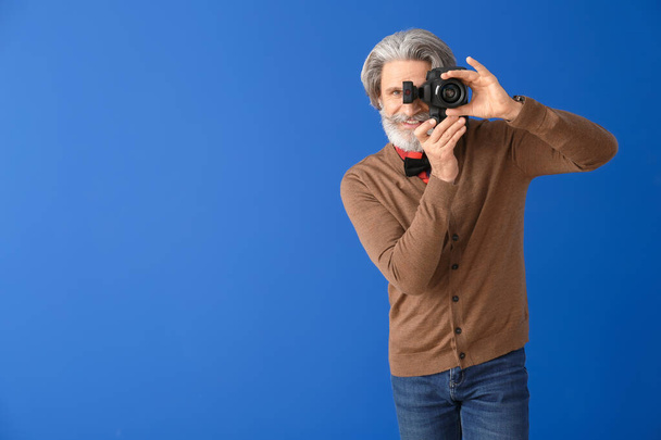 Handsome senior photographer on color background - Photo, Image