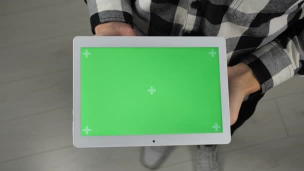 Человек стоит в офисе и держит цифровой планшет с зеленым экраном хрома ключ
 - Кадры, видео