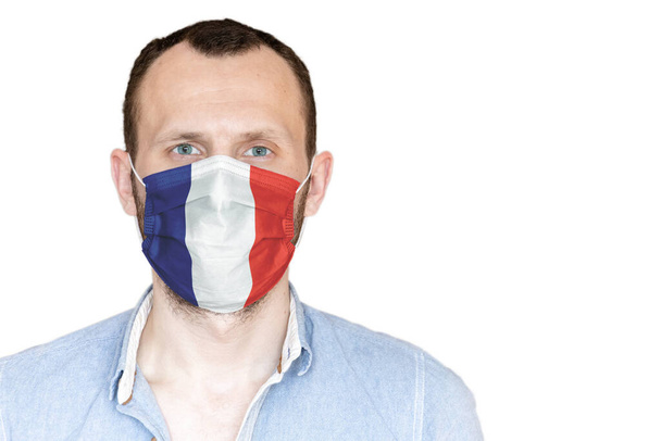 Beyaz bir arka planda Fransa bayrağı olan tıbbi maskeli genç bir adamın portresi. - Fotoğraf, Görsel