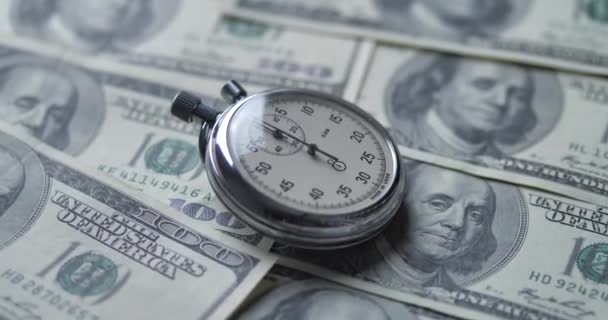 De stopwatch ligt op de dollars. Tijd is geld concept. - Video