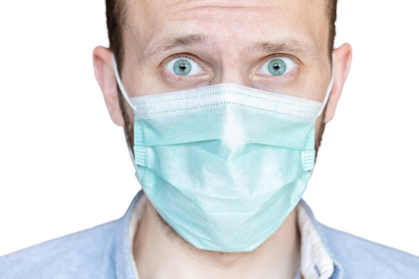primer plano de una cara masculina en una máscara médica con miedo en sus ojos sobre un fondo blanco
 - Foto, Imagen
