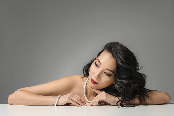 Молодая азиатка с красивыми волосами на сером фоне
 - Фото, изображение