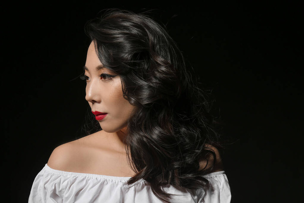 Молодая азиатка с красивыми волосами на темном фоне
 - Фото, изображение