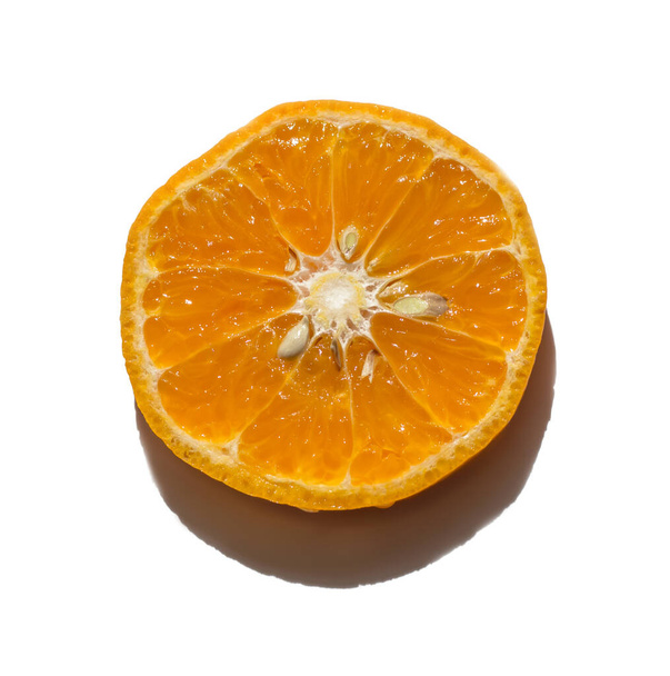 a slice of sweet tangerine on a white background with a deep shadow from the sun. - Фото, изображение