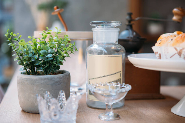 egy évjáratú üvegpalack, amelyet dekorációs növényes edény és a kávépult bárján lévő egyéb dolgok mellé helyeztek - Fotó, kép