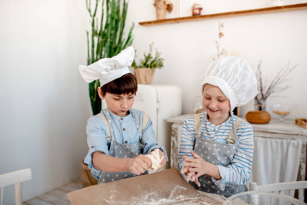 Sister and brother make dough and indulge in flour in the kitchen - Photo, image