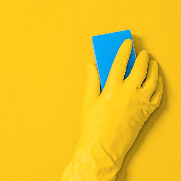 Hand in rubber handschoen met veeg voor het reinigen veegt het oppervlak van stof, vuil en bacteriën. Commercieel schoonmaakbedrijf - Foto, afbeelding