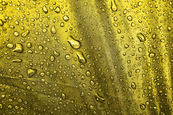 L'eau tombe sur le tissu. Gouttes d'eau sur fond jaune. Condensé. gouttes d'eau fond
.  - Photo, image
