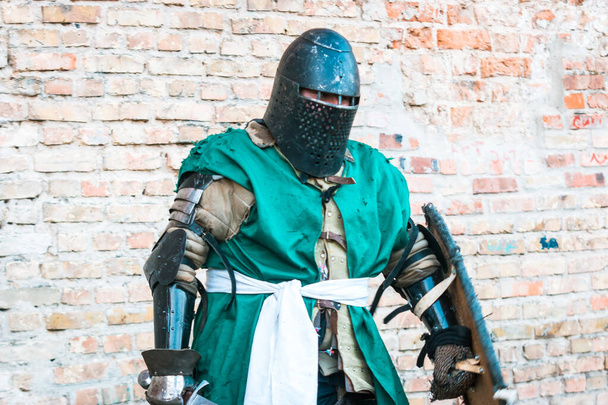 Średniowieczny rycerz w zbroi. Zielone ubrania. Historyczne przywrócenie wydarzeń wojskowych. - Zdjęcie, obraz
