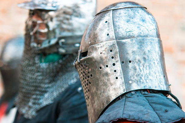 Twee middeleeuwse ridders in harnas. Fragment van een helm. Imitatie, herstel van militaire operaties, gevechten. - Foto, afbeelding