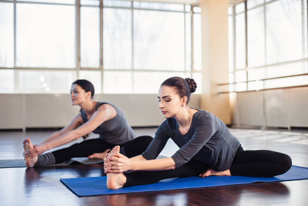 Zwei junge Frauen beim Stretching im Fitnessraum - Foto, Bild