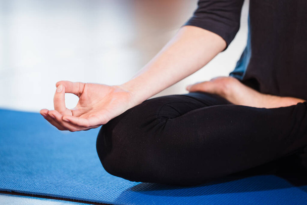Yoga menina meditando interior e fazendo um símbolo zen com a mão. Close-up do corpo da mulher em ioga posar em um tapete verde
 - Foto, Imagem