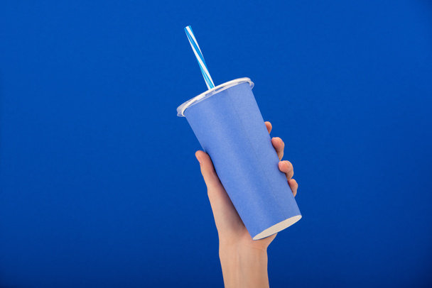 cropped view of woman holding paper cup with soft drink isolated on blue - 写真・画像