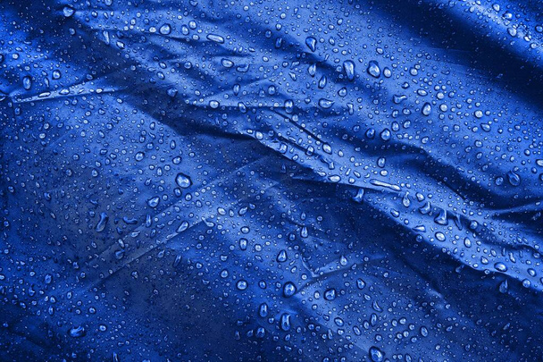 L'eau tombe sur le tissu. L'eau tombe sur fond bleu. Condensé. gouttes d'eau fond
.  - Photo, image
