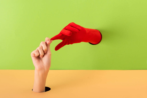 cropped view of woman taking off red glove on green and orange - Foto, immagini