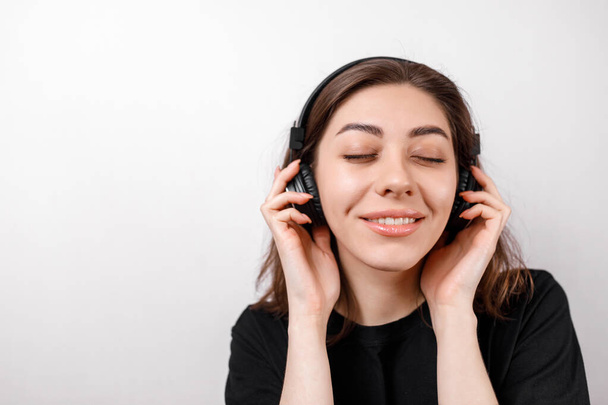 Mutlu esmer kadın, beyaz arka planda kulaklıkla müzik dinlerken gülümsüyor. izole - Fotoğraf, Görsel