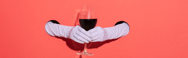 panoramic shot of woman in gloves holding glass with red wine on red - Fotografie, Obrázek