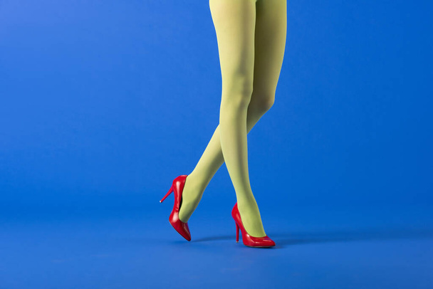 cropped view of trendy model in green tights and red heels standing on blue  - Photo, Image