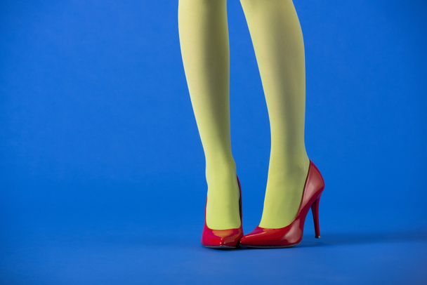 cropped view of model in green tights and bright heels posing on blue  - Photo, Image