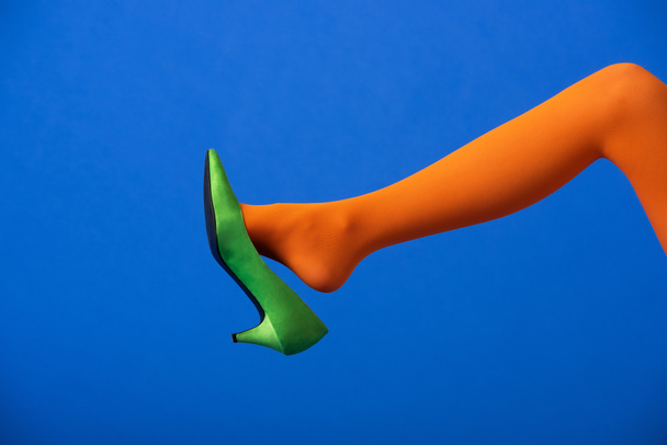 cropped view of woman in bright orange tights and green shoe on blue - Photo, Image