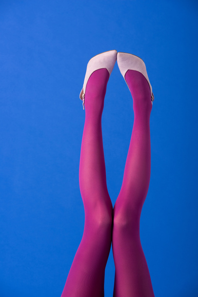 vista ritagliata del modello in collant viola e calzature in posa su blu
 - Foto, immagini