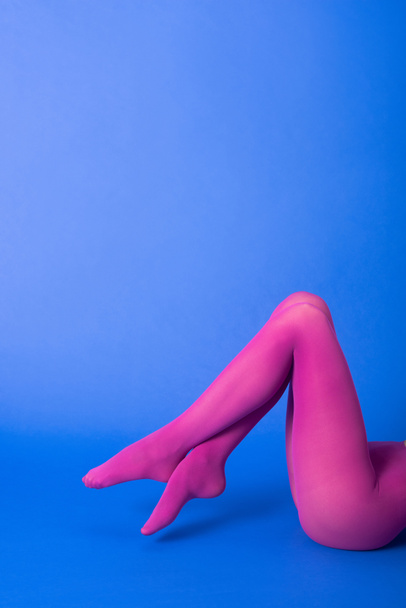обрезанный вид женщины в ярко-фиолетовых колготках позируя на синий
 - Фото, изображение
