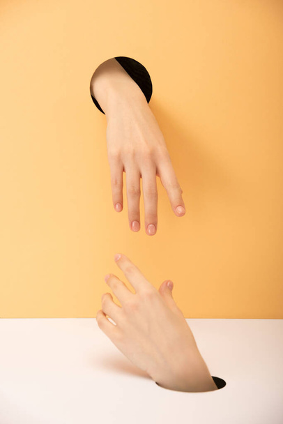 oříznutý pohled na ruce na oranžové a bílé  - Fotografie, Obrázek