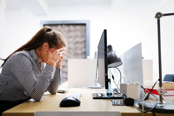 Overworked and frustrated young business woman in front of computer in office - Foto, imagen