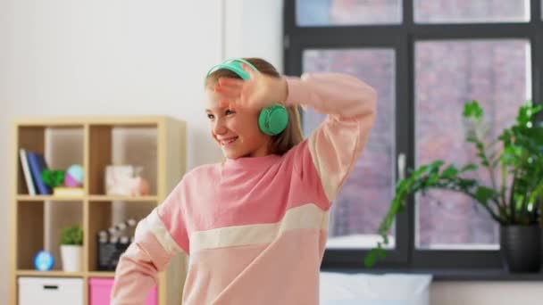 happy smiling girl in headphones dancing at home - Materiał filmowy, wideo