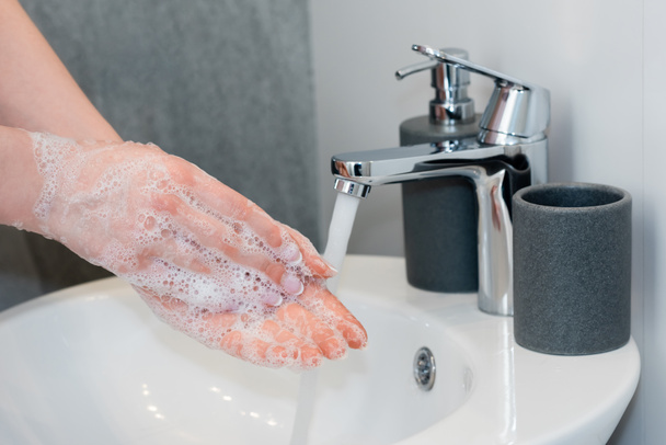 vista ritagliata di giovane donna che lava le mani saponate in bagno
  - Foto, immagini