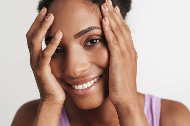 Portrait of african american joyful woman covering her face and smiling isolated over white background - Foto, Imagem