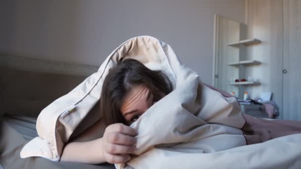 pretty girl hides in blanket on large bed in hotel room - Video, Çekim
