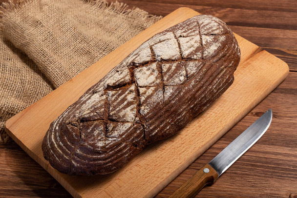 Fresh baked bread at wooden table - Foto, afbeelding