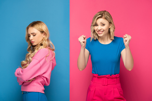 Vrolijke vrouw tonen ja gebaar in de buurt trieste blonde zus op roze en blauwe achtergrond - Foto, afbeelding