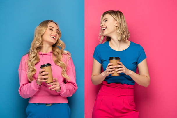 Χαρούμενα ξανθά κορίτσια με χάρτινα φλιτζάνια σε ροζ και μπλε φόντο - Φωτογραφία, εικόνα