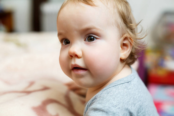 Photo portrait of a baby girl with pink cheeks. Baby gets to his feet - Foto, Imagem