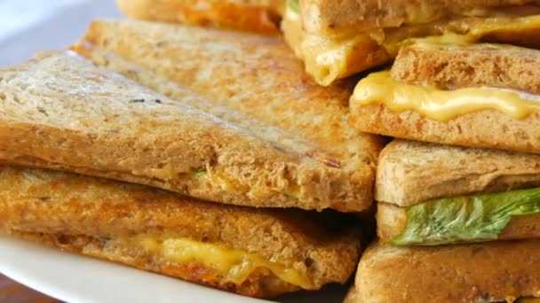 Πρωινό στην κουζίνα του σπιτιού. Σάντουιτς ή τοστιέρες με μπέικον, τυρί τσένταρ και μαρούλι περιστρέφονται από κοντά. - Πλάνα, βίντεο