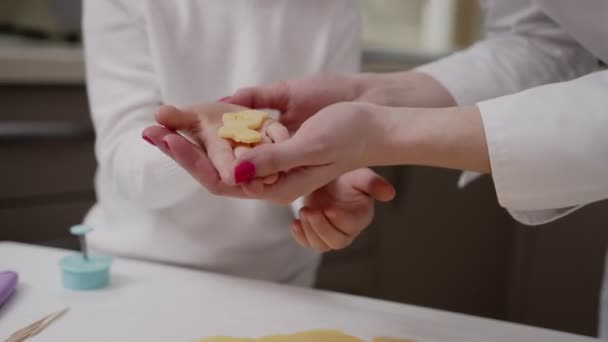 Női kezek kivágott tészta cookie alakú, kis kezét a gyermek segít, tökéletes teasütemény tészta fehér pergamenen - Felvétel, videó