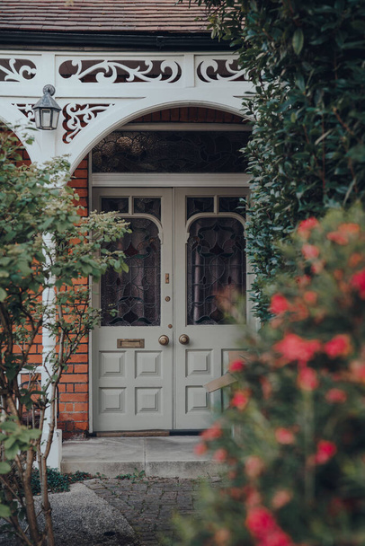 Puerta frontal de vidrieras de una casa tradicional eduardiana en Londres, Reino Unido, enfoque selectivo, enmarcado por árboles
. - Foto, Imagen