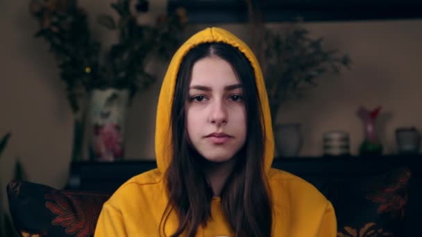 A young girl winks and shows her tongue. Close-up of a European girl in a yellow jacket and hood. The concept of a relationship, all right. - Footage, Video