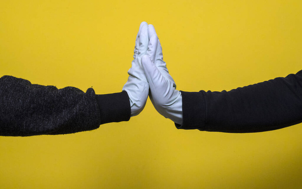 El apretón de manos de las personas con los guantes azules médicos sobre el fondo amarillo. Concepto epidémico de Coronavirus
. - Foto, imagen