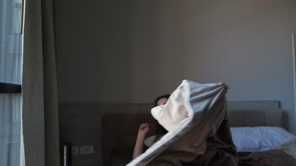 happy woman in black pajama awakes in bed in hotel room - Filmati, video