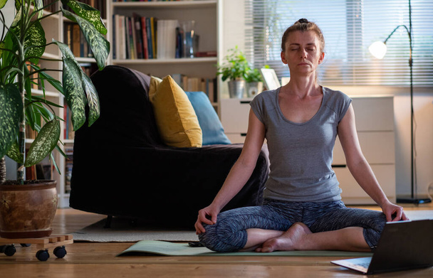 жінка робить тренування йоги вдома дивитися відео онлайн на портативному комп'ютері
 - Фото, зображення