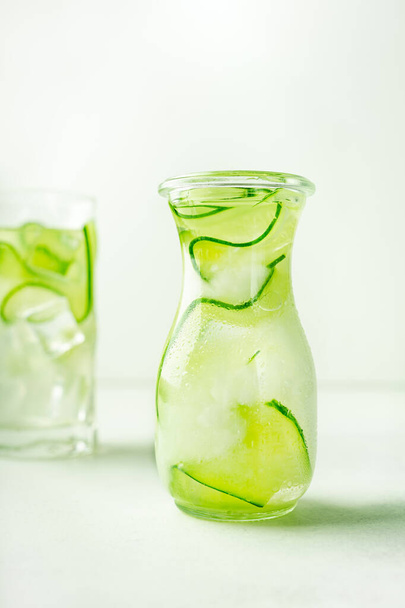 Cucumber infused water in glass jar and highball glass. Portrait orientation, with copy space - Fotó, kép
