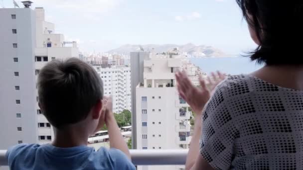 Familienangehörige applaudieren dem medizinischen Personal vom Balkon. Menschen klatschen während der Coronavirus-Pandemie auf Balkonen und Fenstern zur Unterstützung von Gesundheitspersonal, Ärzten und Krankenschwestern - Filmmaterial, Video