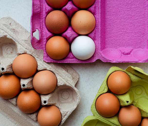 Fresh brown and white eggs in multicolored cardboard containers, top view. Horizontal image - Photo, Image