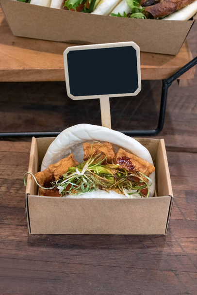 Una hamburguesa vegetariana de tofu colocada en una caja de cartón para la venta un mostrador de restaurante
 - Foto, Imagen