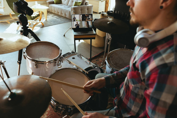 Caucasian musician playing drumms during online concert or sound-check with the band at home isolated and quarantined, focus on laptop - 写真・画像